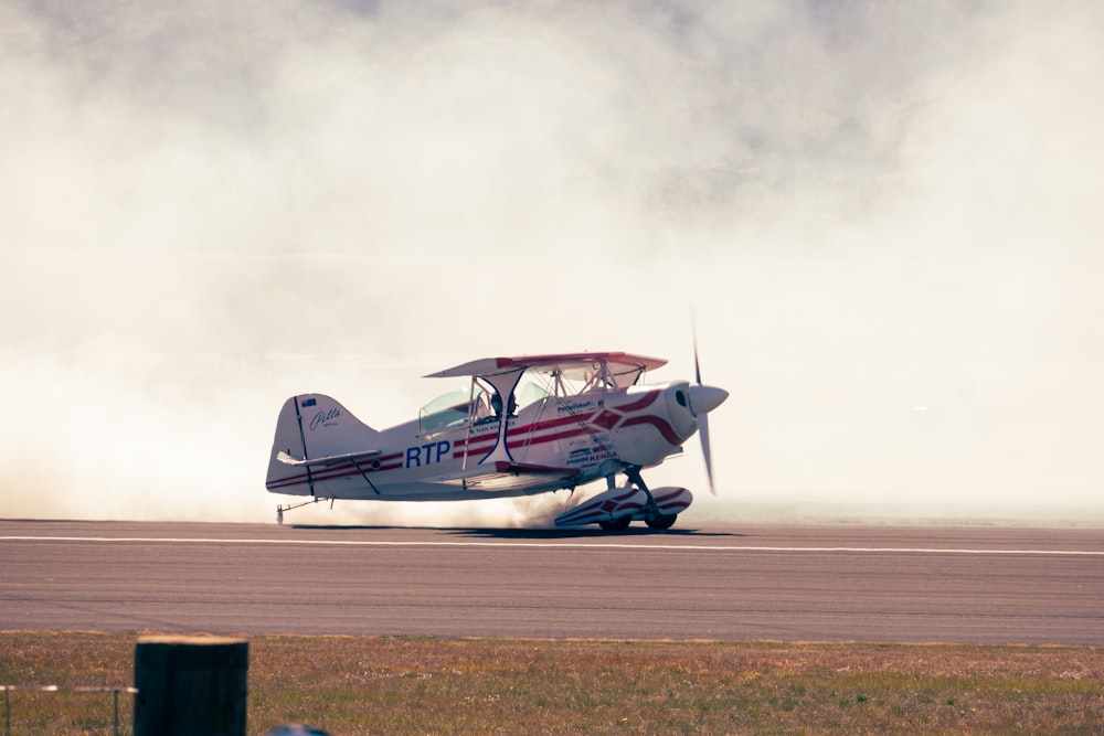 a small propeller plane on a runway with smoke coming out of it