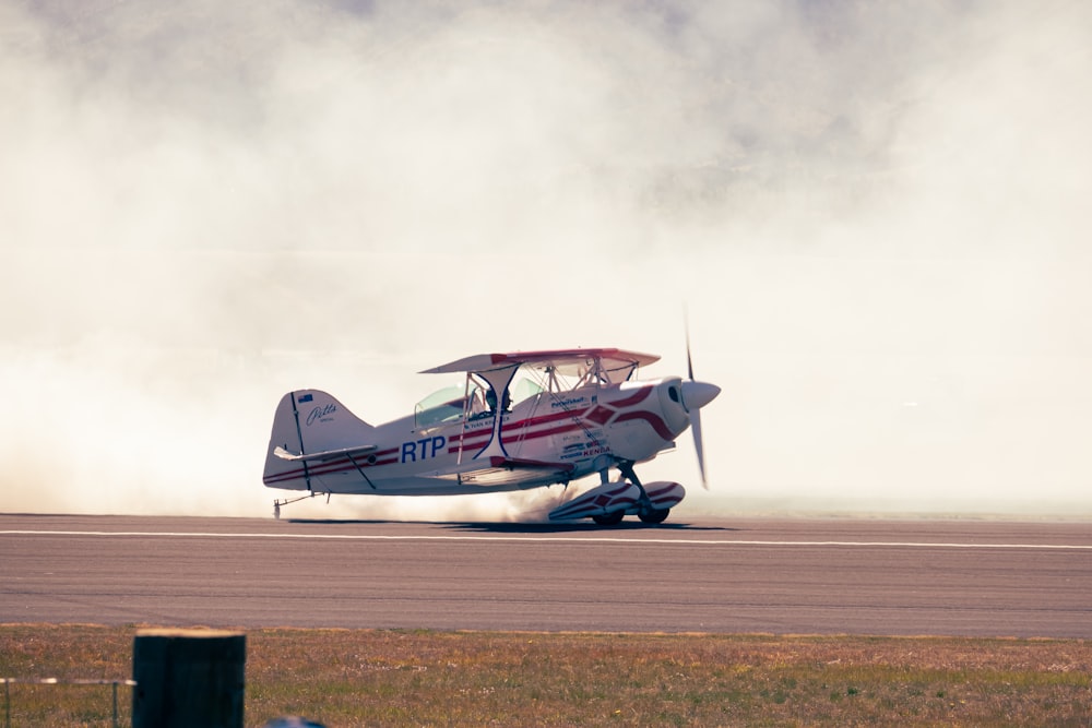 un petit avion à hélices sur une piste d’où s’échappe de la fumée ;