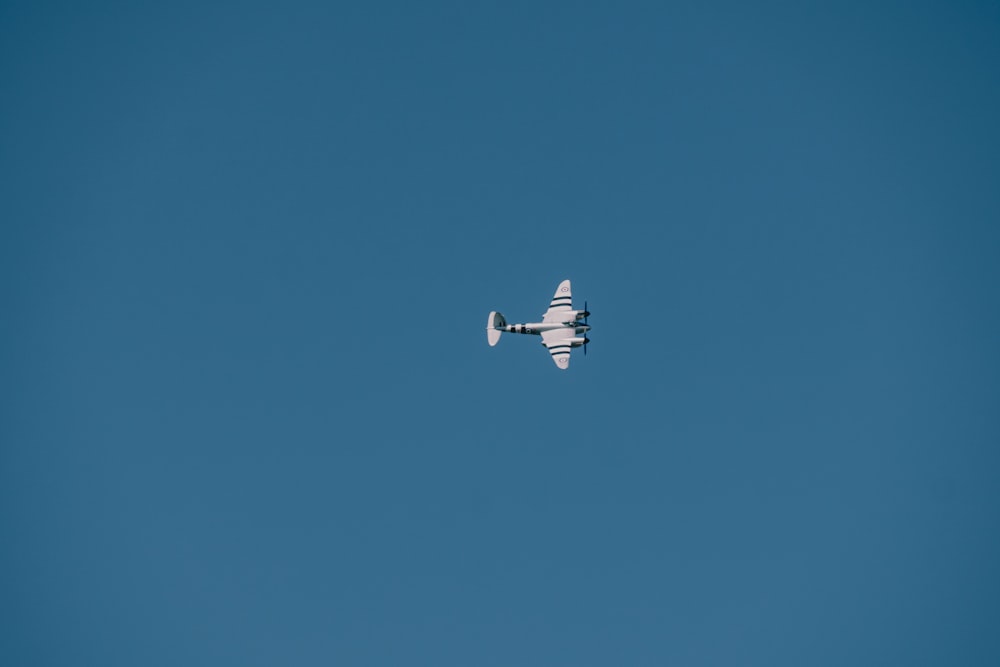 a small airplane flying through a blue sky