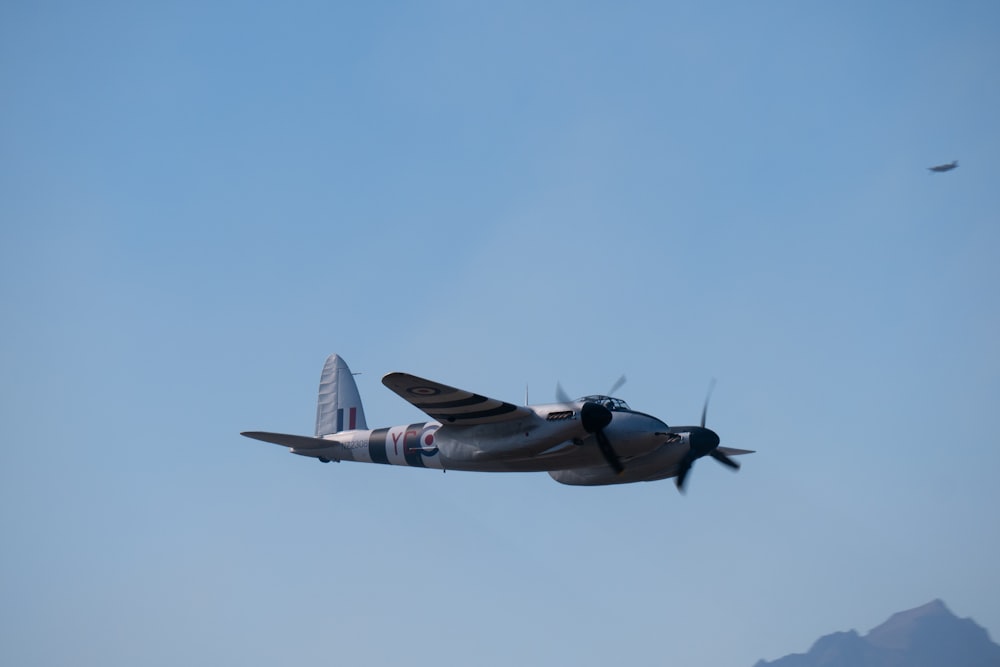 a plane flying in the sky with a mountain in the background