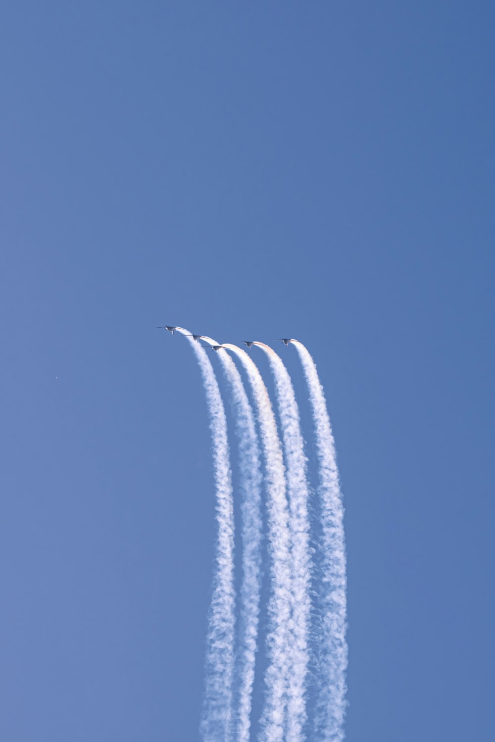 a group of jets flying through a blue sky