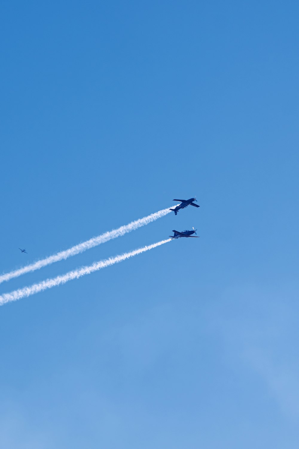 Zwei Jets, die in entgegengesetzte Richtungen am blauen Himmel fliegen