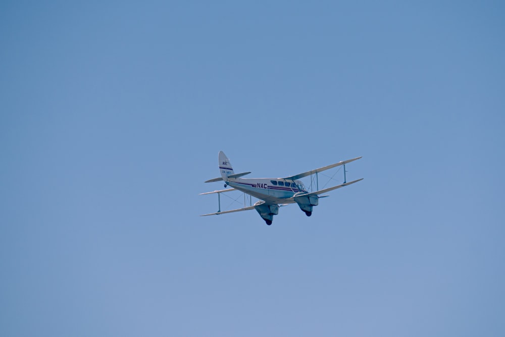 a small airplane flying through a blue sky