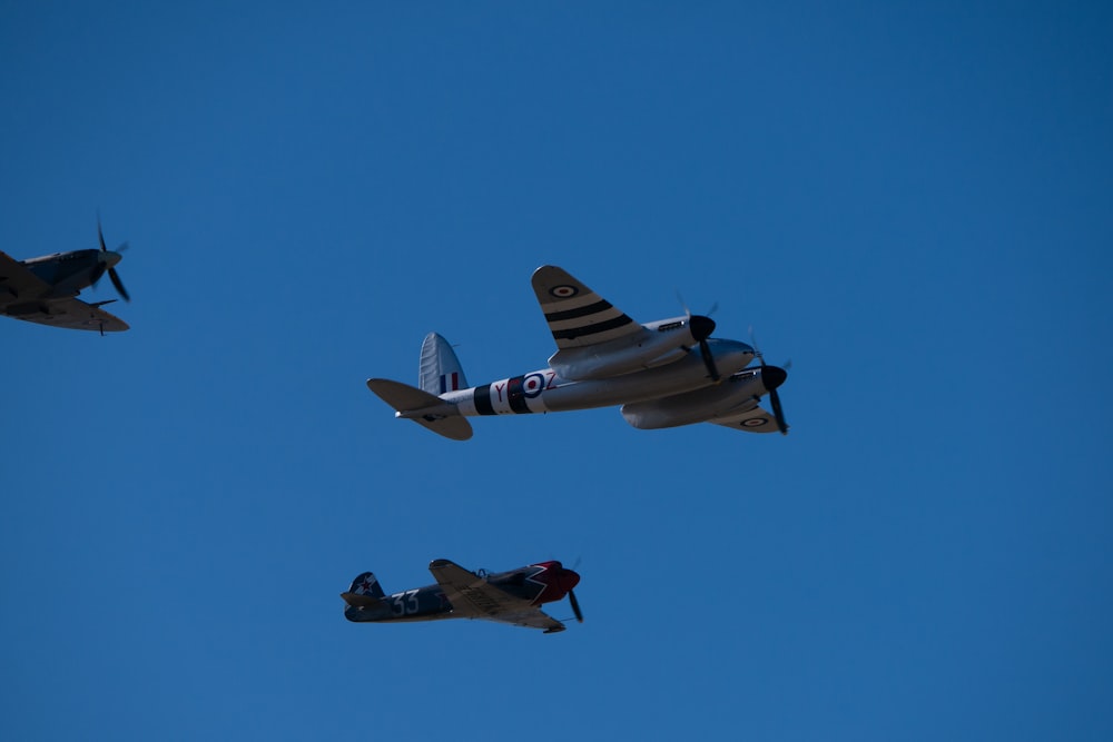 Trois avions volant dans les airs avec un ciel bleu derrière eux