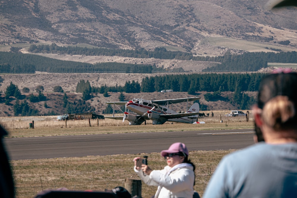 uma mulher tirando uma foto de um avião na pista