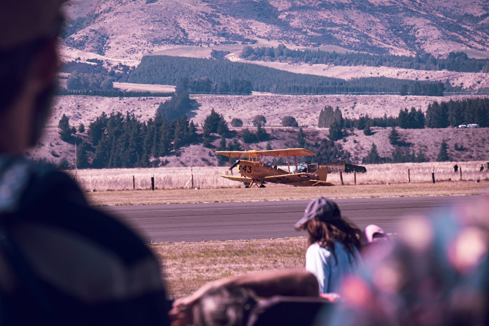 a group of people watching a small plane on a runway