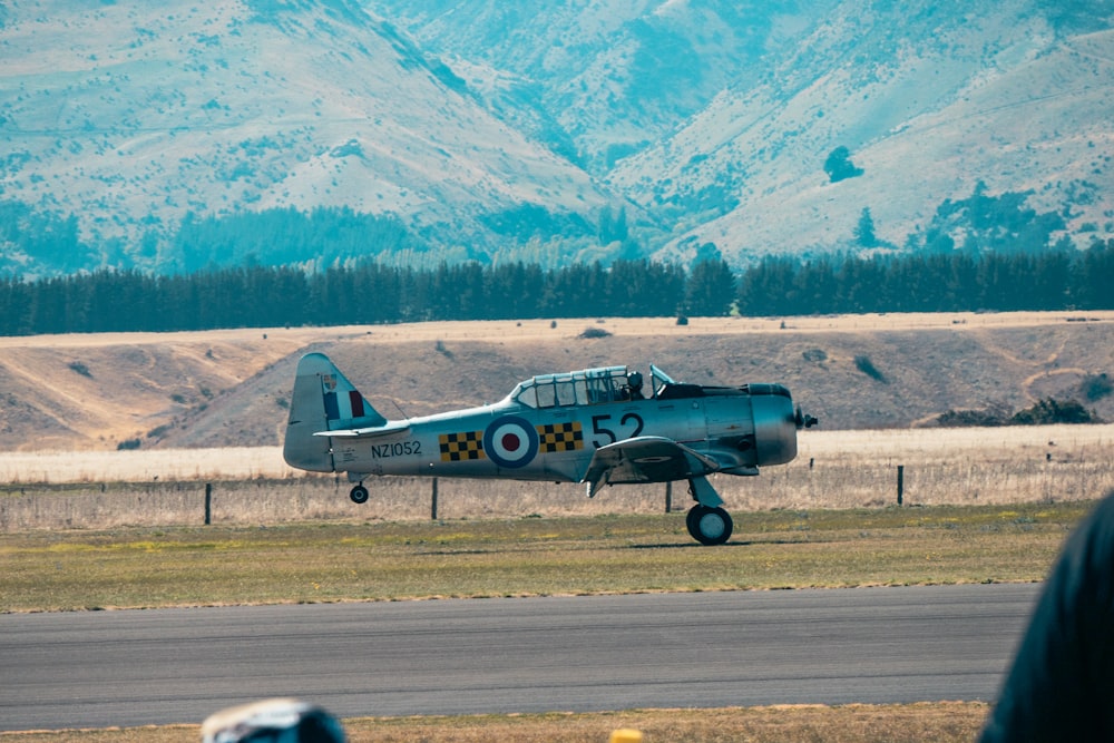 a small airplane is on a runway with mountains in the background