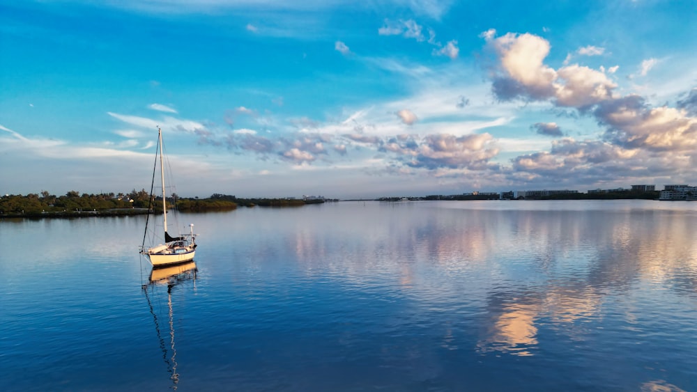 a sailboat floating on a lake under a cloudy blue sky