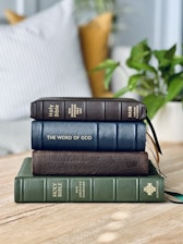 a stack of three books sitting on top of a wooden table