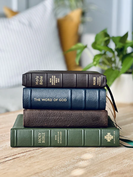 a stack of three books sitting on top of a wooden table