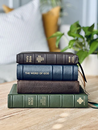 a stack of three books sitting on top of a wooden table