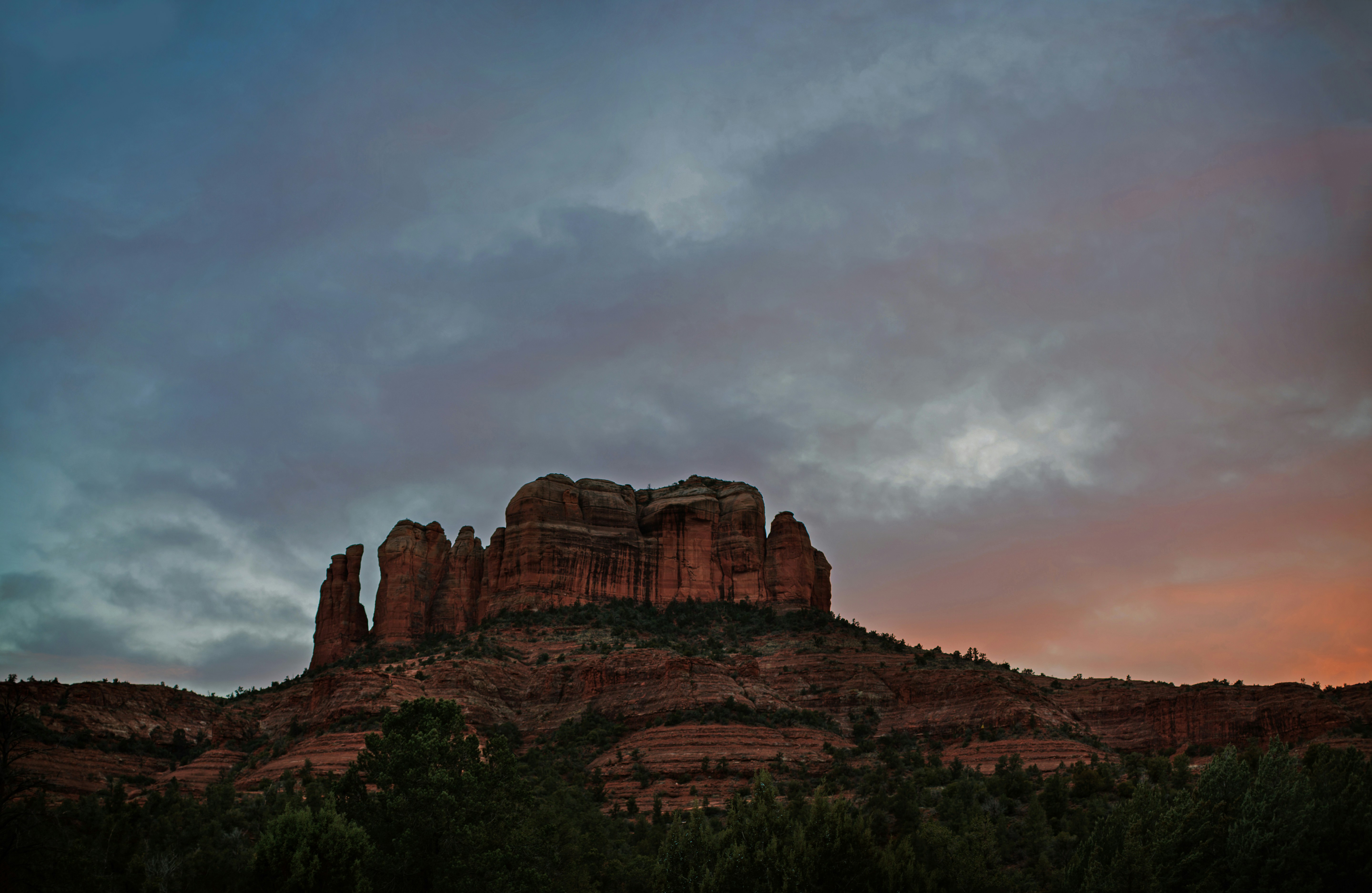 a red rock formation with a cloudy sky in the background