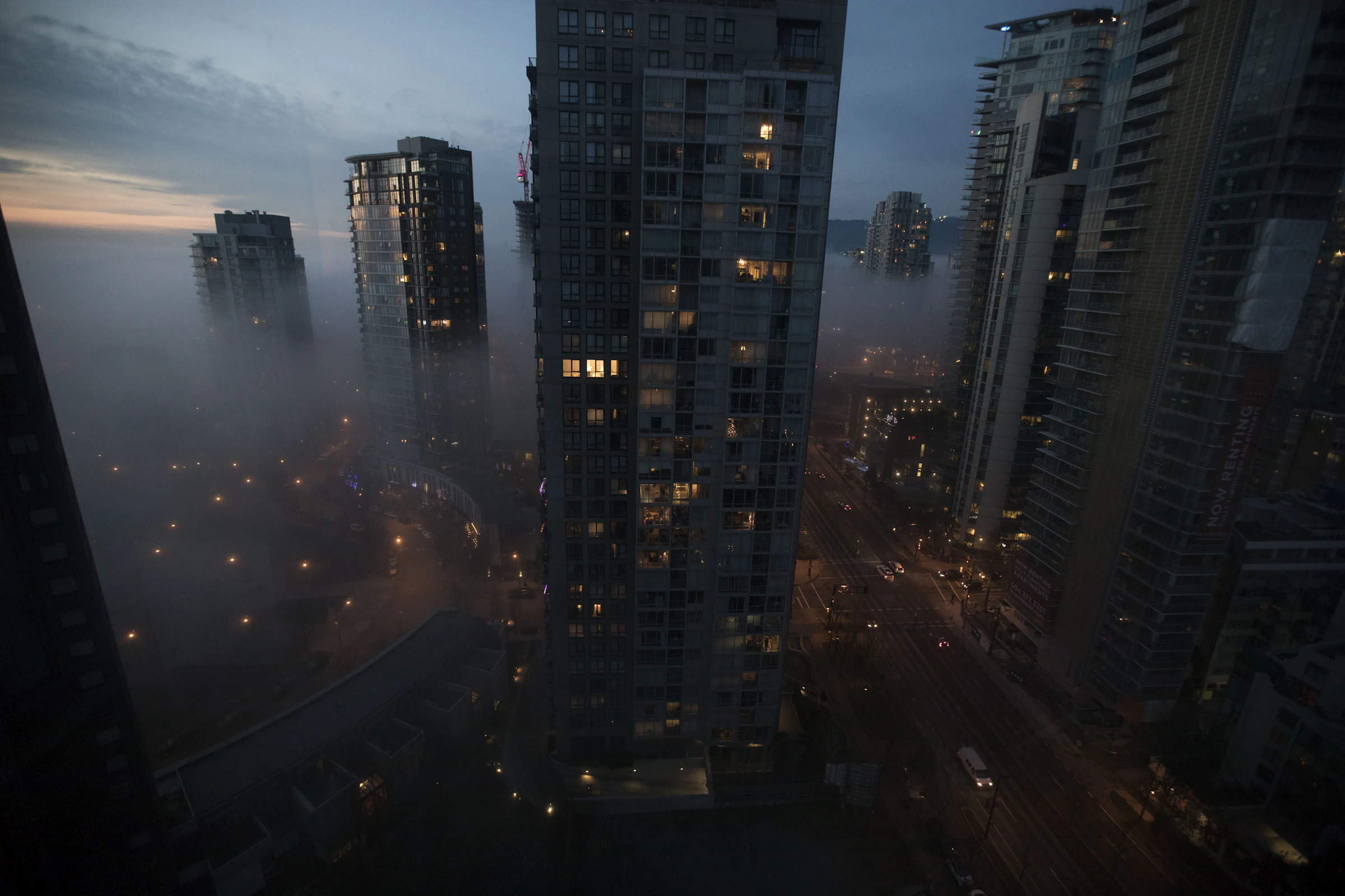 Vancouver towers in fog at night, a few windows still lit