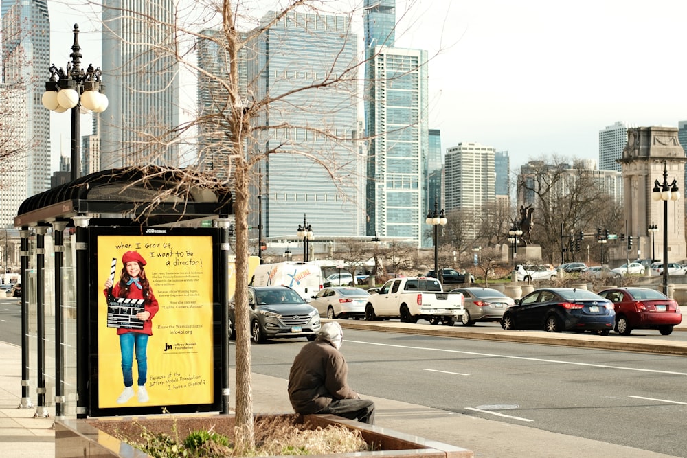 a man sitting on a bench next to a street