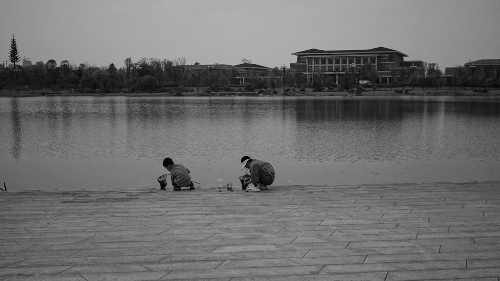 a couple of people sitting on the side of a lake