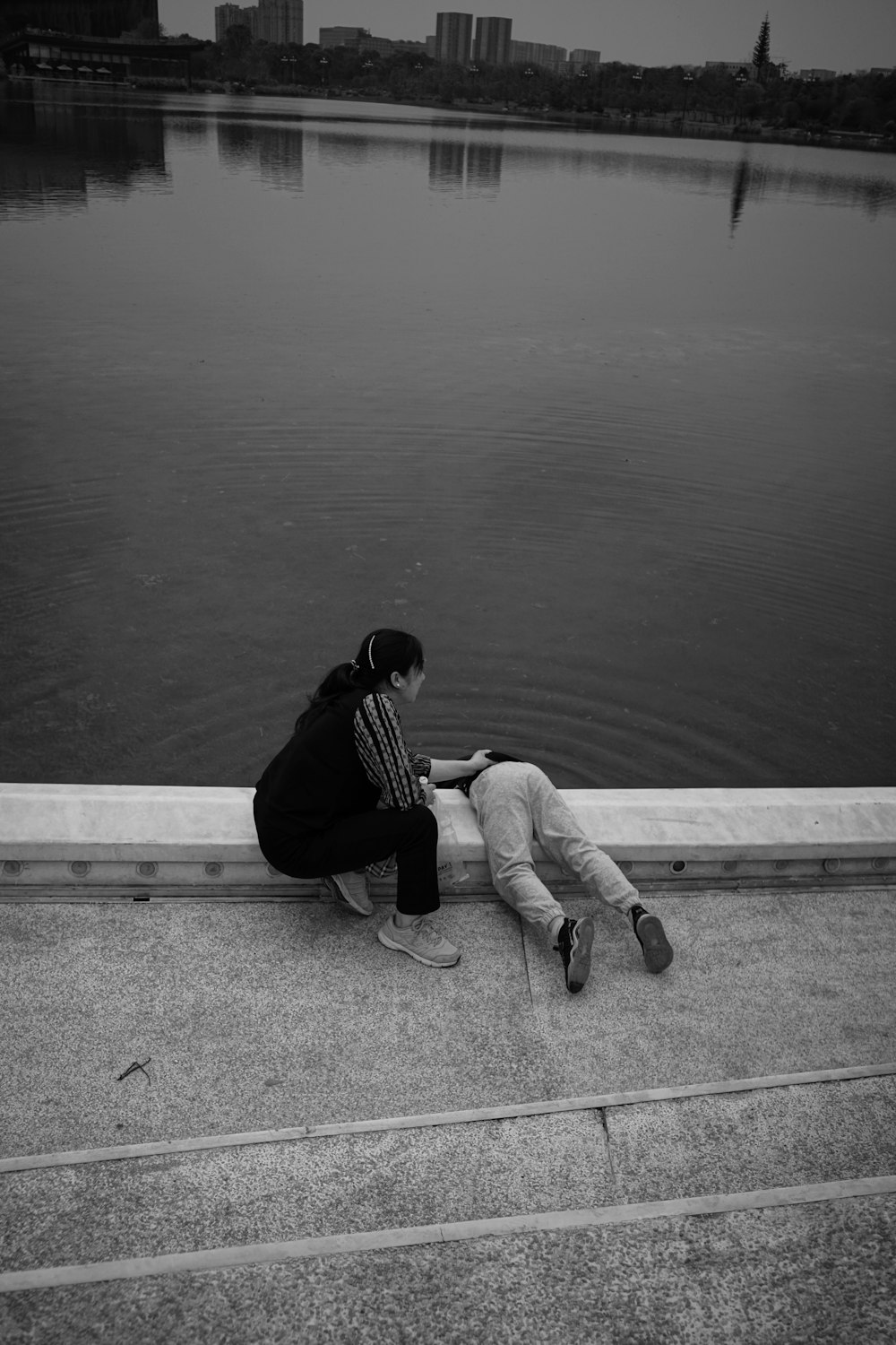 a couple of people sitting next to a body of water