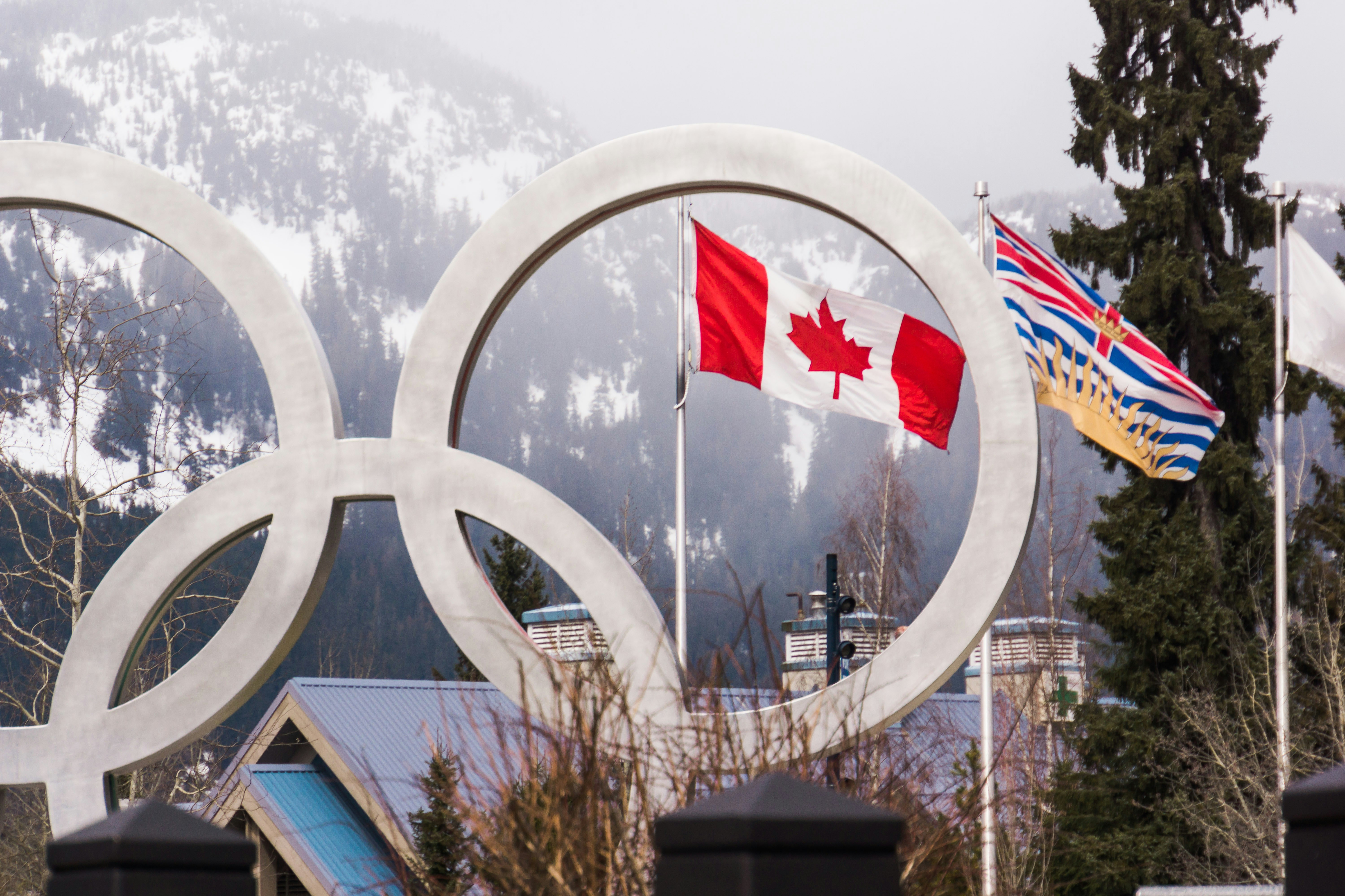 Die Olympischen Ringe mit kanadischer und kanadischer Flagge vor einem Berg
