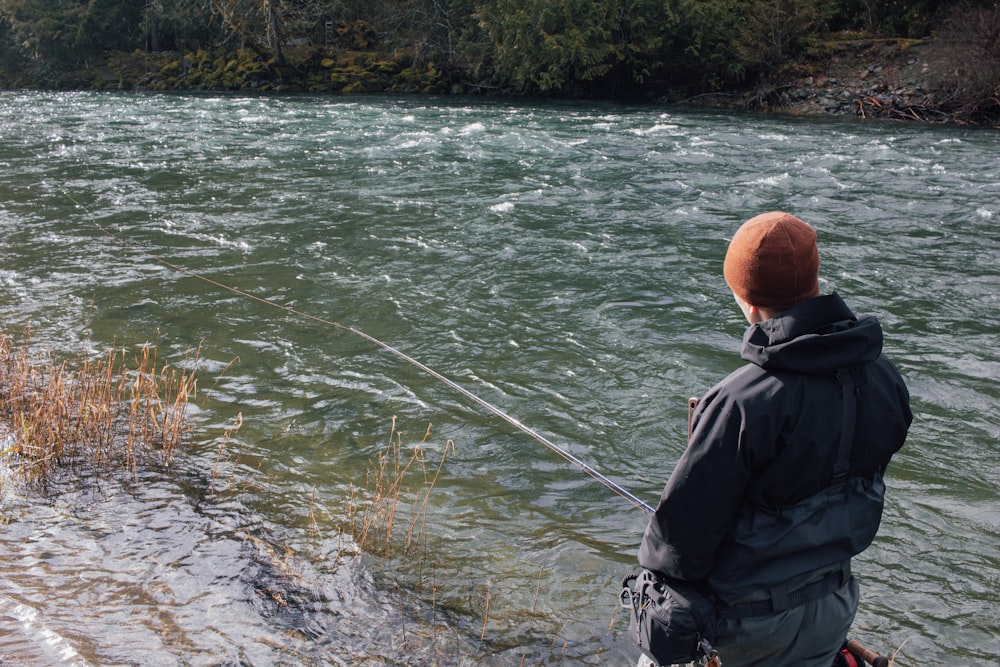 a man standing on a river bank while fishing