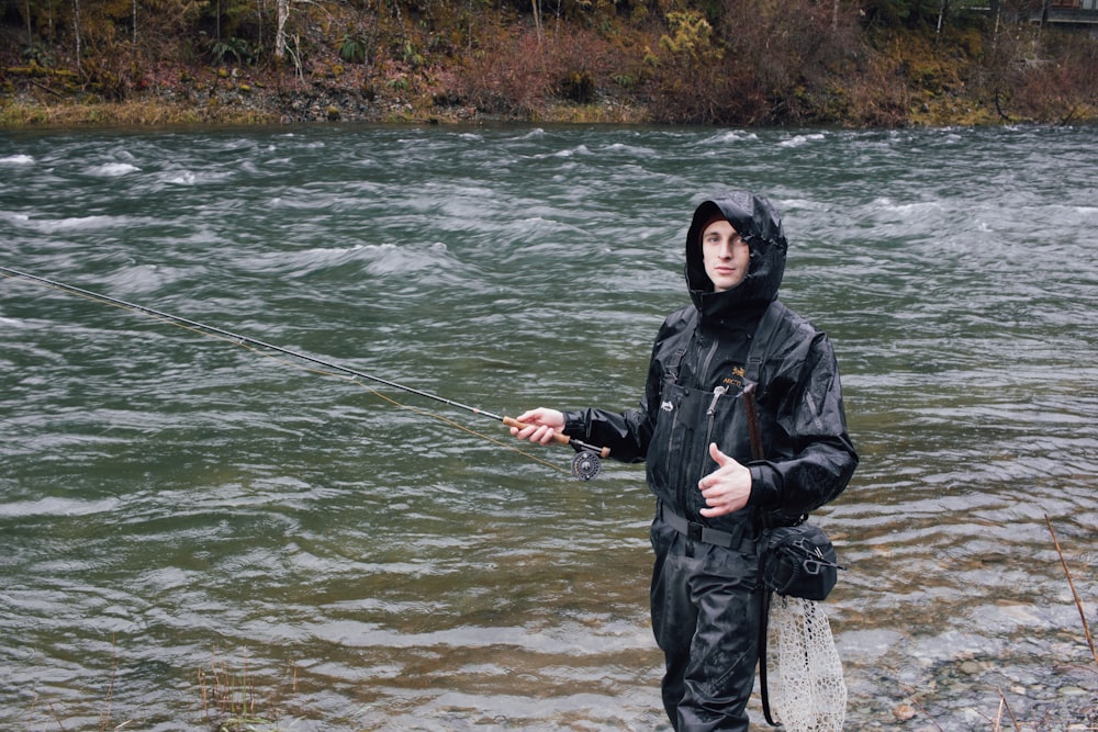 a man standing in a river while holding a fishing pole