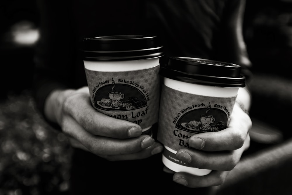 two people holding coffee cups in their hands