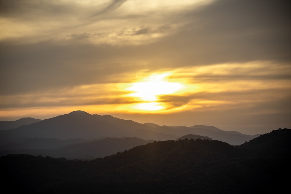 the sun is setting over a mountain range