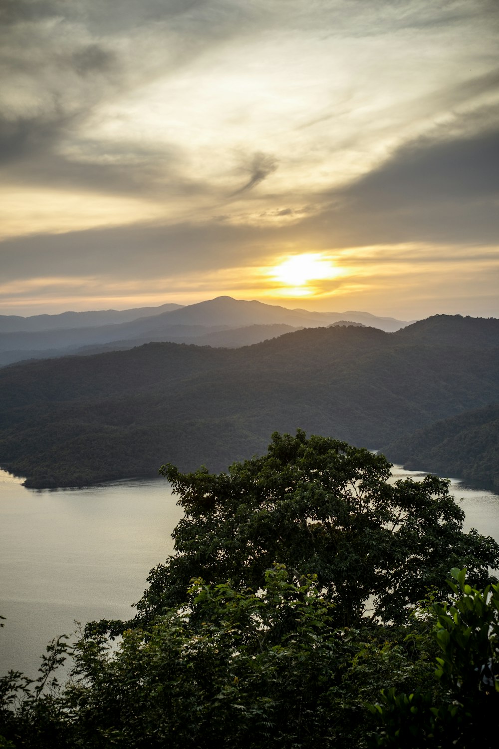 the sun is setting over a lake in the mountains