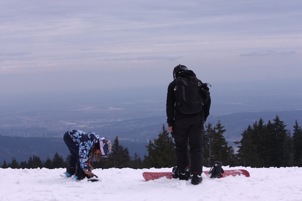 two snowboarders are standing in the snow with their boards