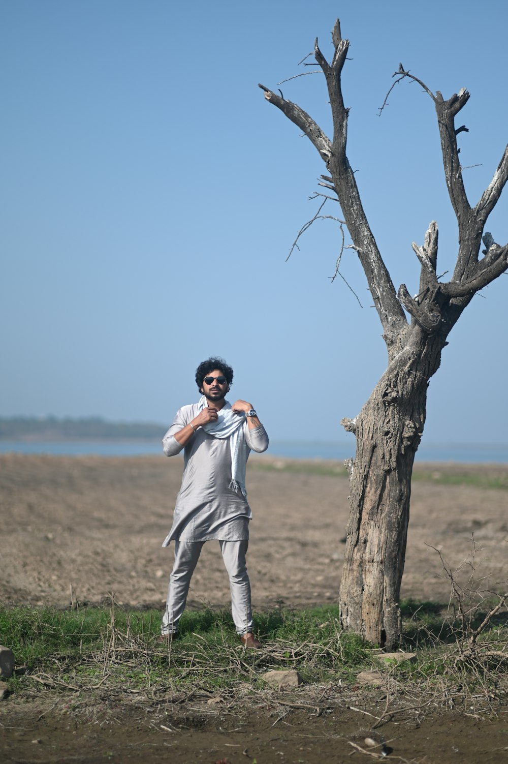 a man standing in front of a dead tree