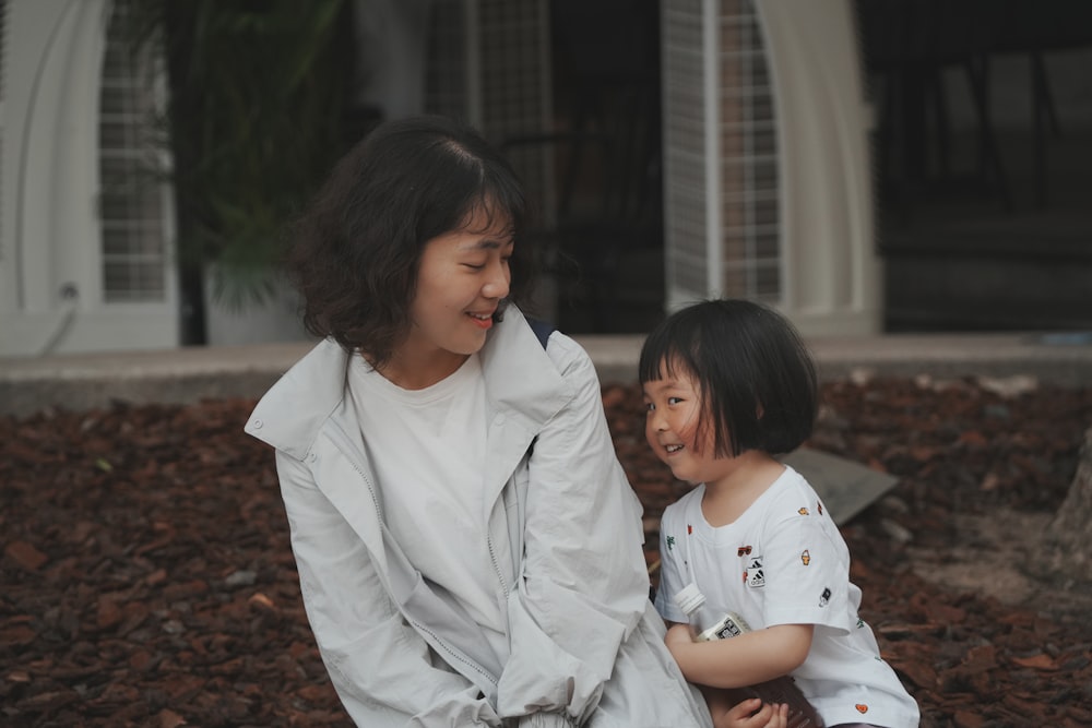 a woman sitting next to a little girl