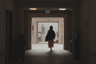 a woman walking down a hallway in a building