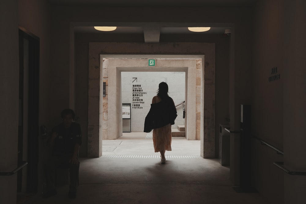 a woman walking down a hallway in a building