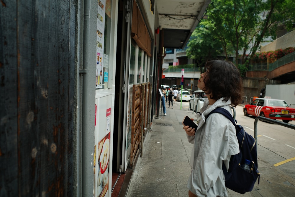 a woman standing on a sidewalk looking at her cell phone