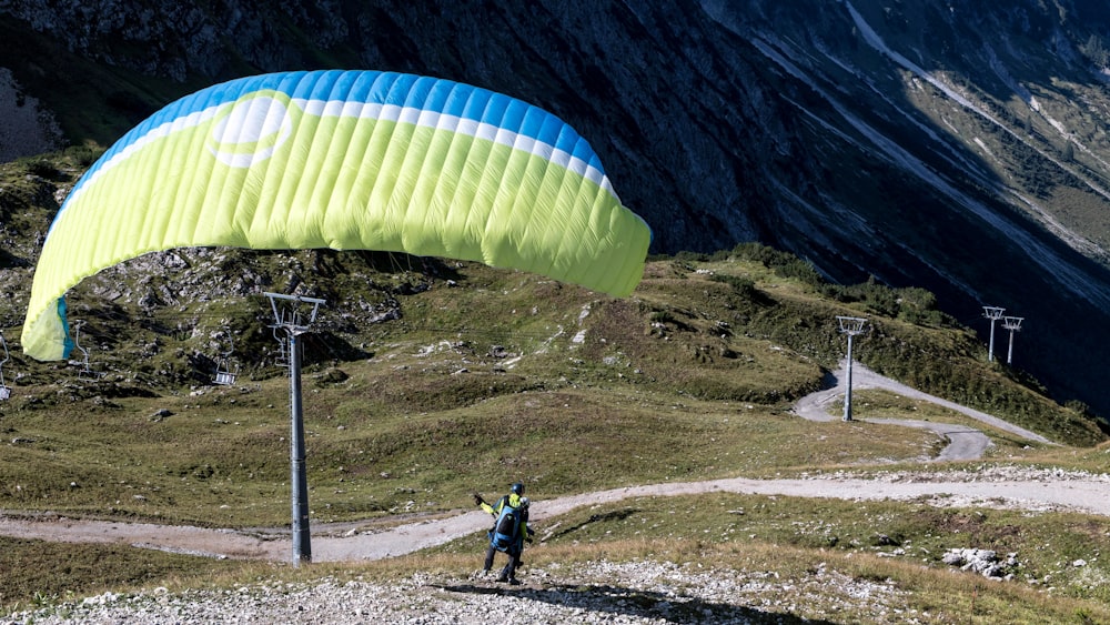 a person standing under a large blue and yellow kite