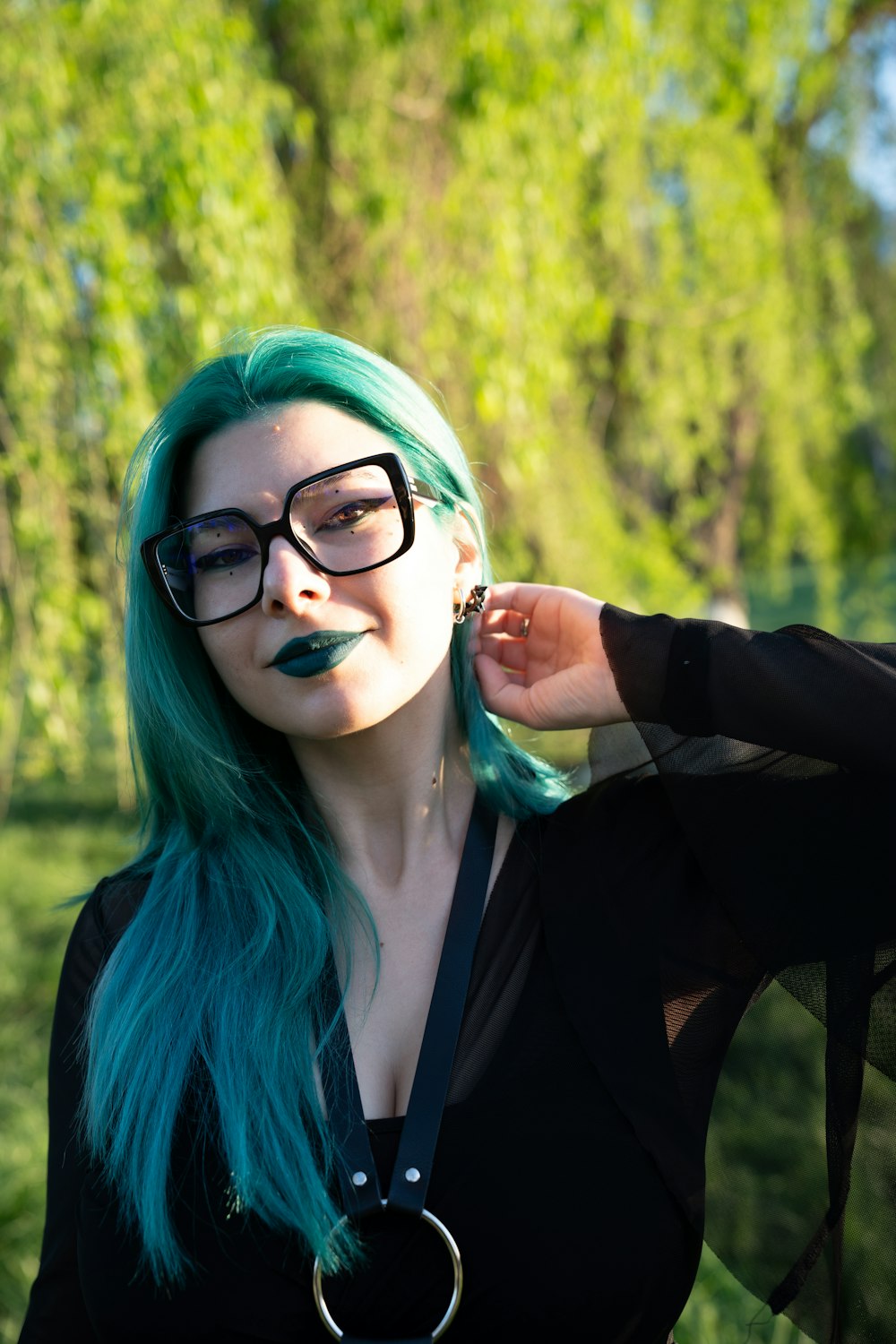 a woman with green hair and black glasses