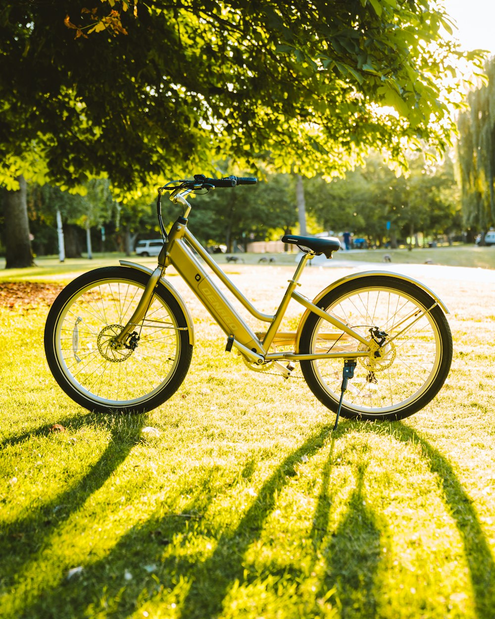 a bicycle parked in the grass near a tree