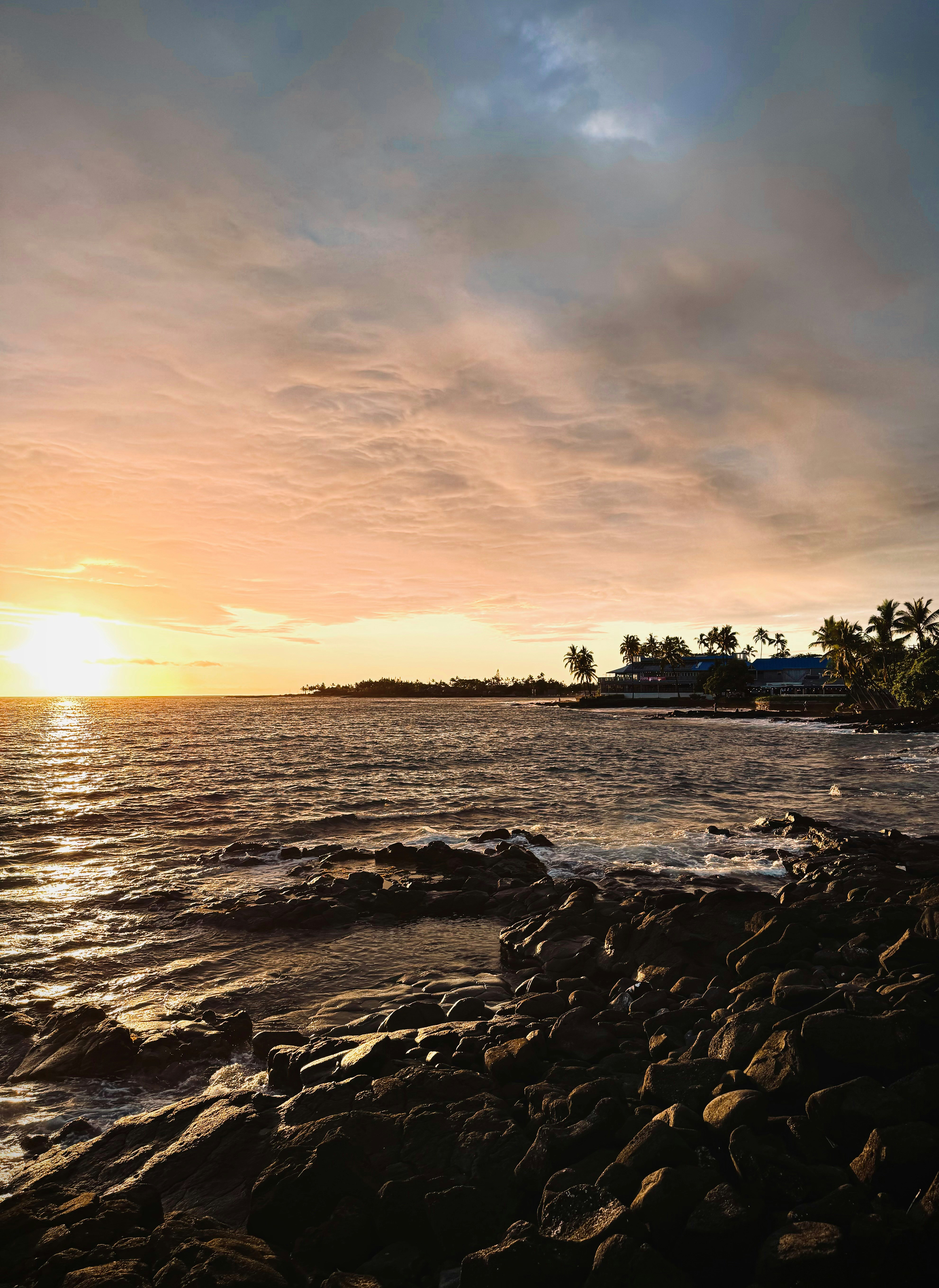 the sun is setting over a rocky beach