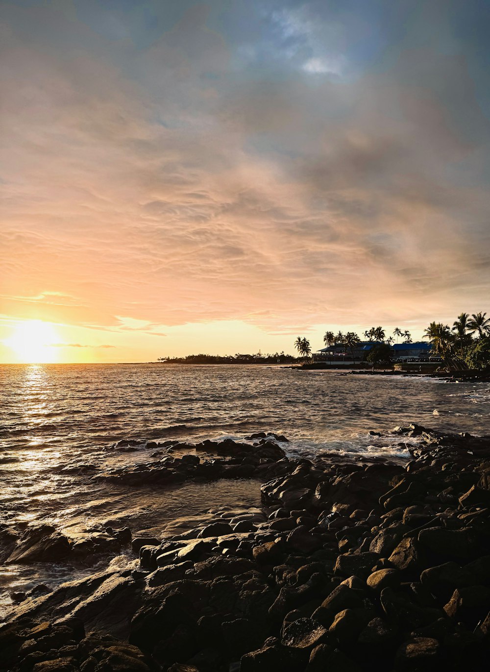 the sun is setting over a rocky beach