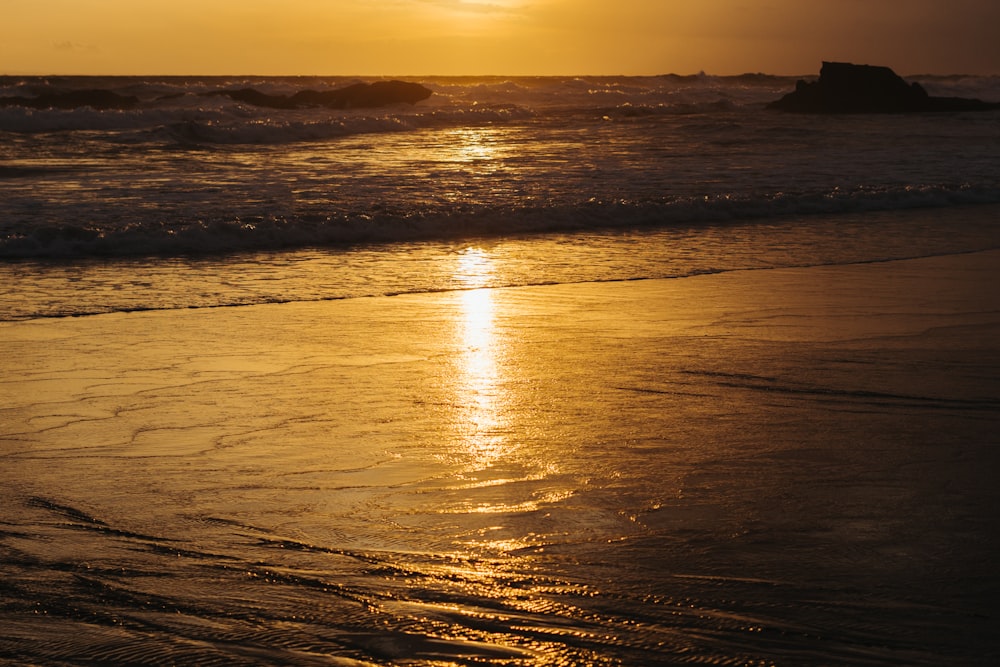 the sun is setting over the water at the beach