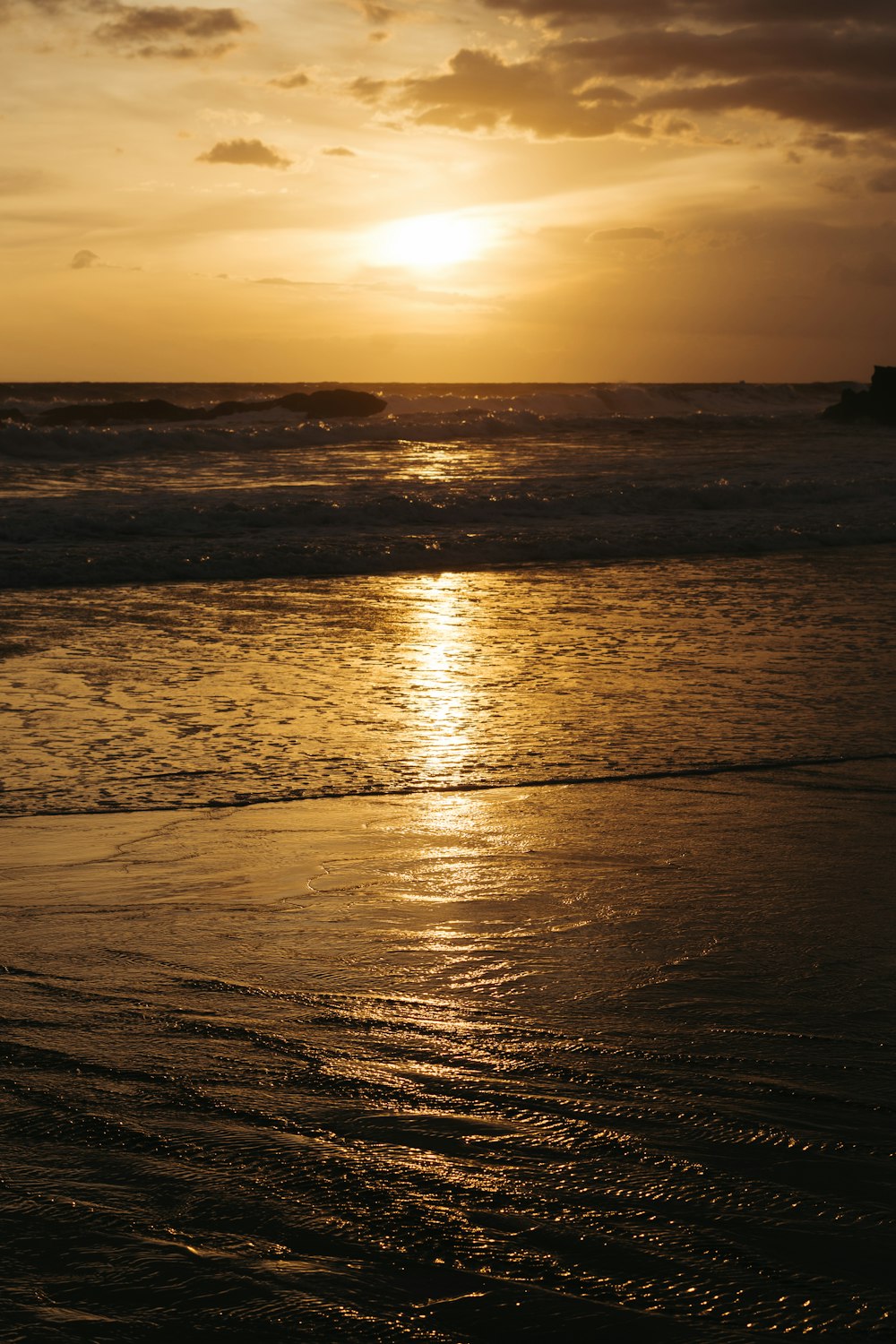 the sun is setting over the ocean on the beach