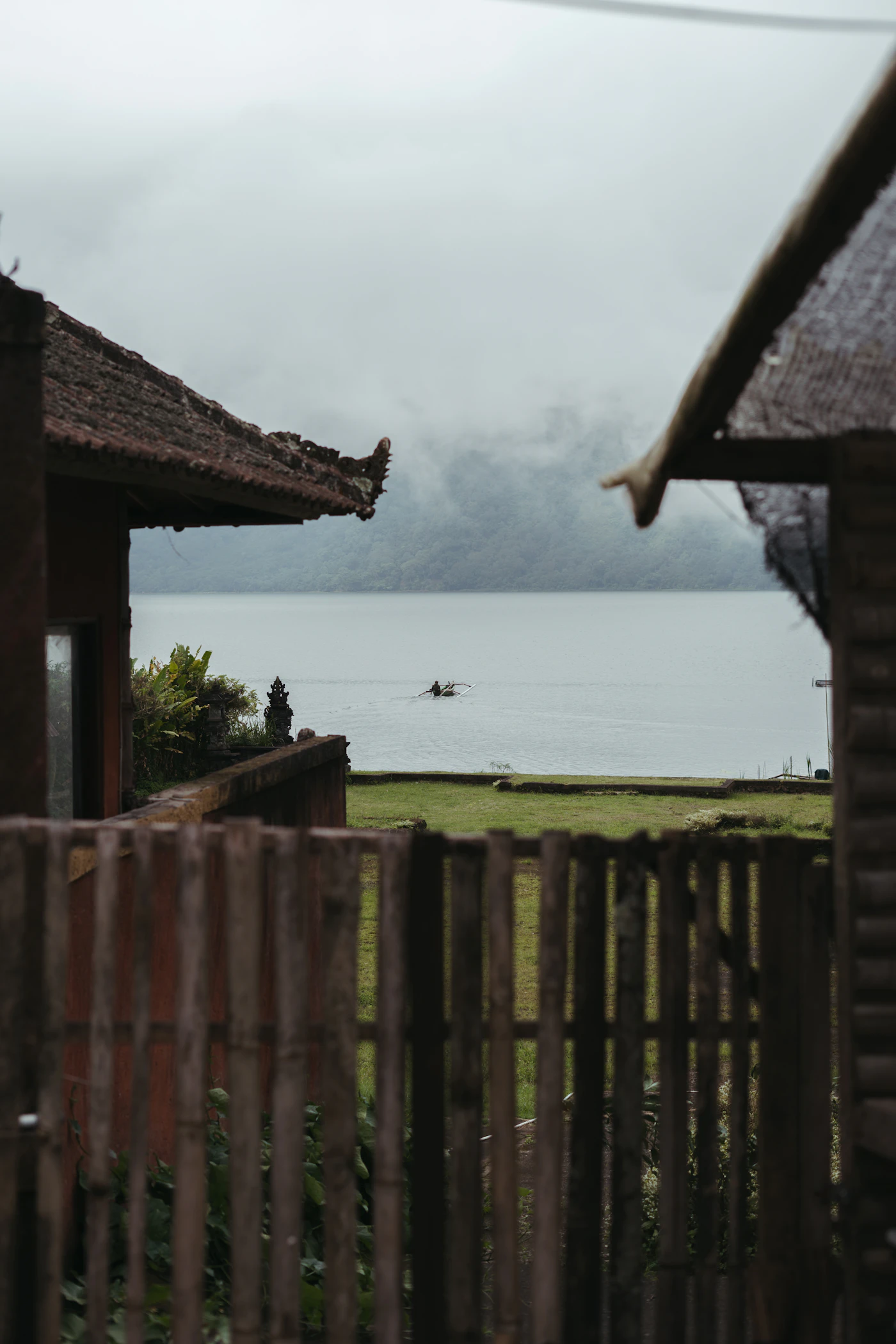 View of a calm highland lake in Bali seen from a traditional wooden pavilion