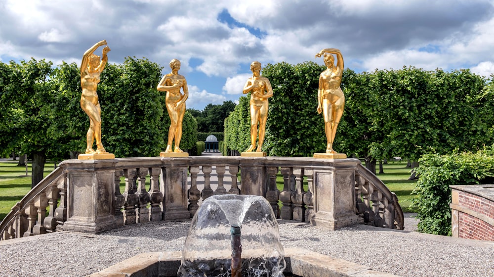 une fontaine surmontée de trois statues dorées