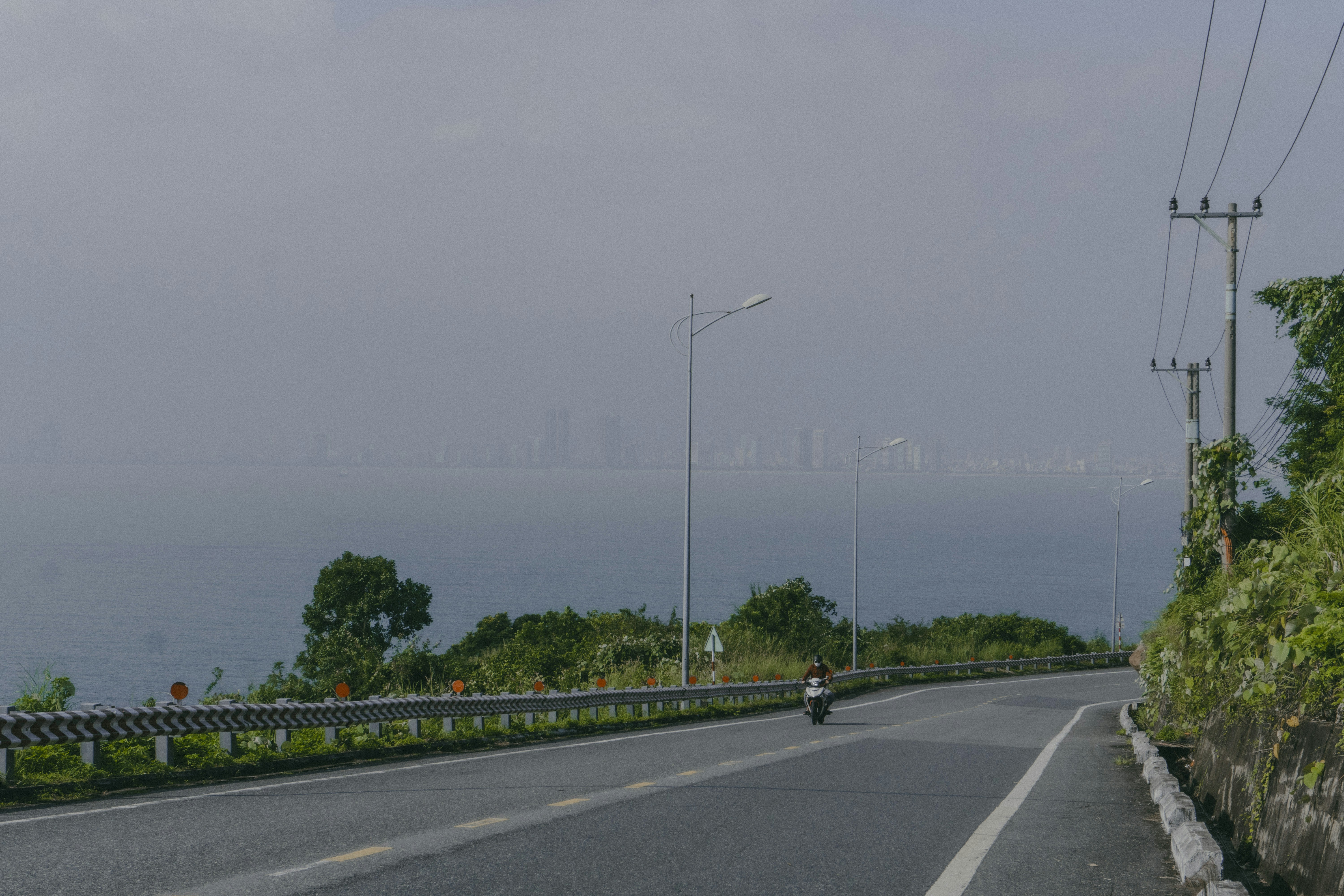a person riding a motorcycle down a road next to the ocean, 