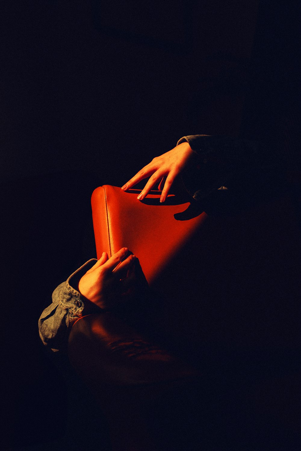 a person holding a red suitcase in the dark