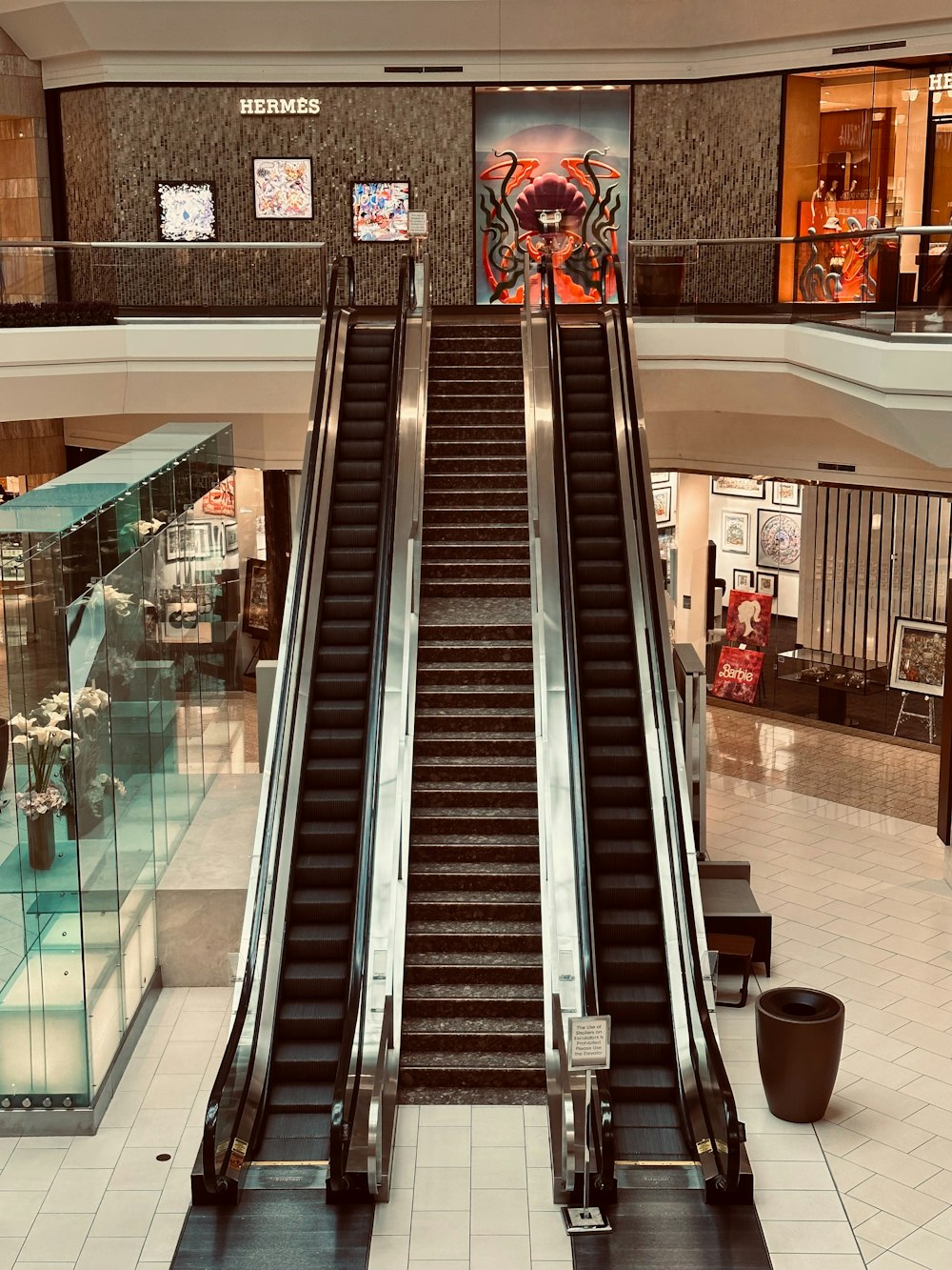 an escalator in a shopping mall with a giant spider on the wall