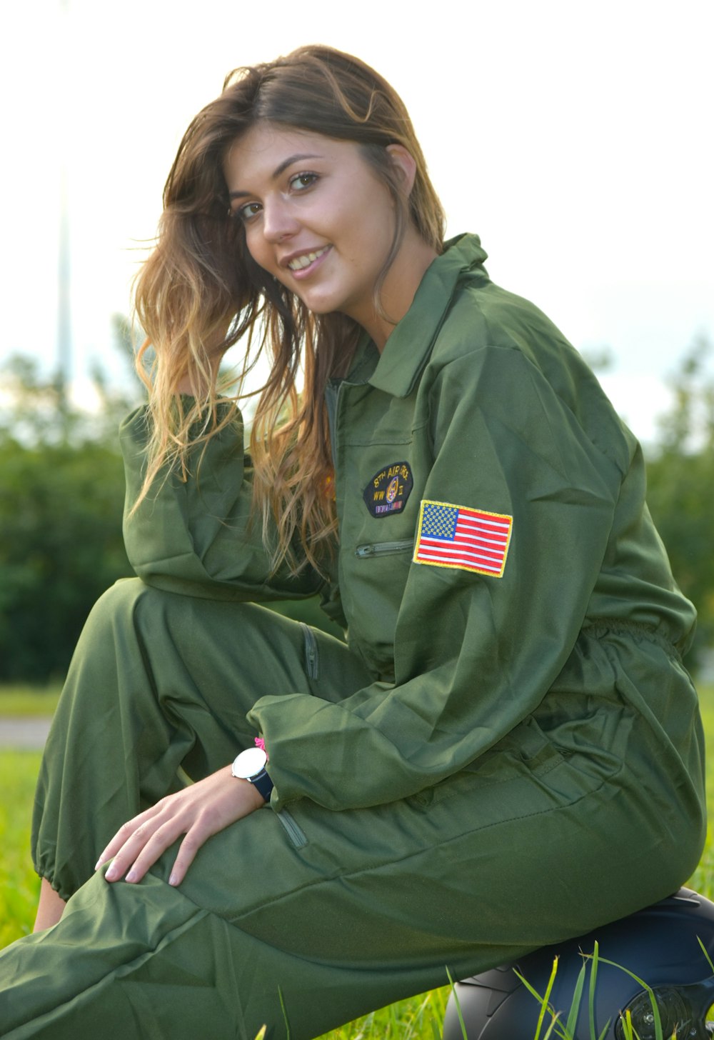 a woman in a green uniform sitting in the grass