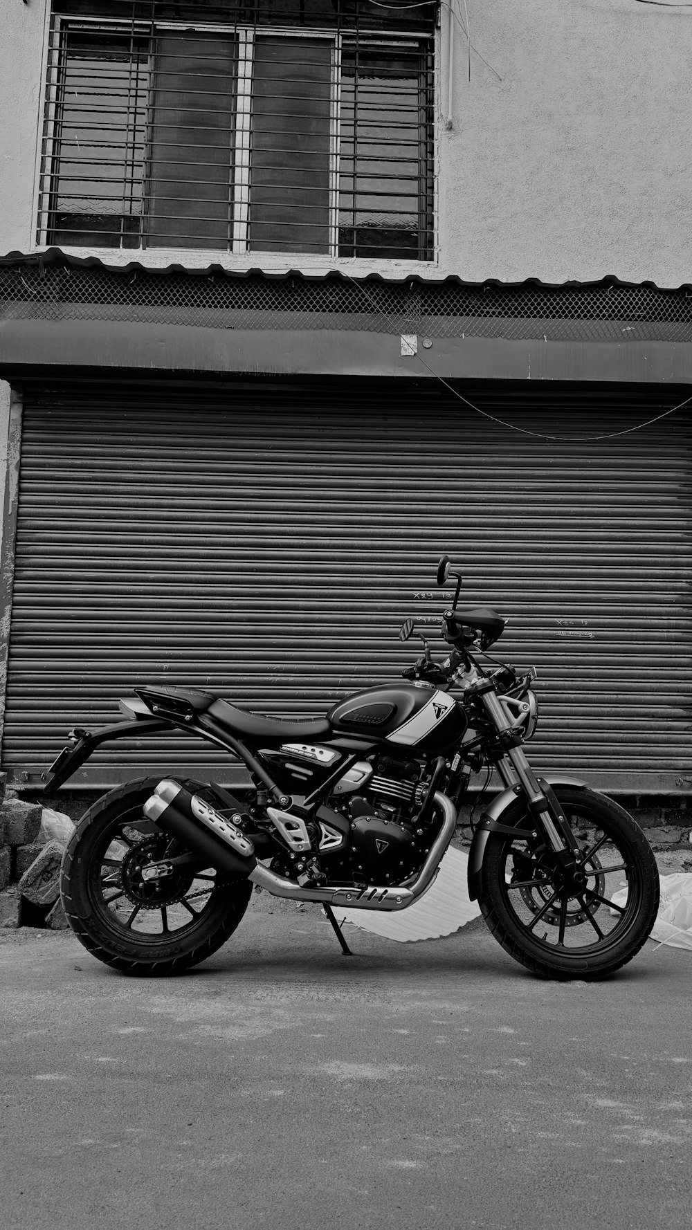 a black and white photo of a motorcycle parked in front of a building