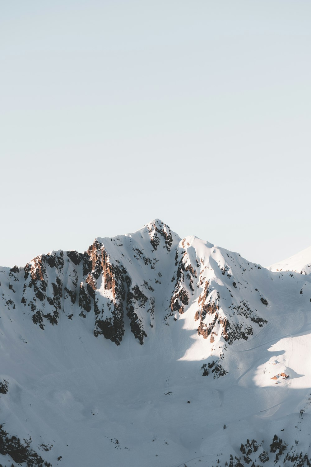 a snow covered mountain with a person on a snowboard