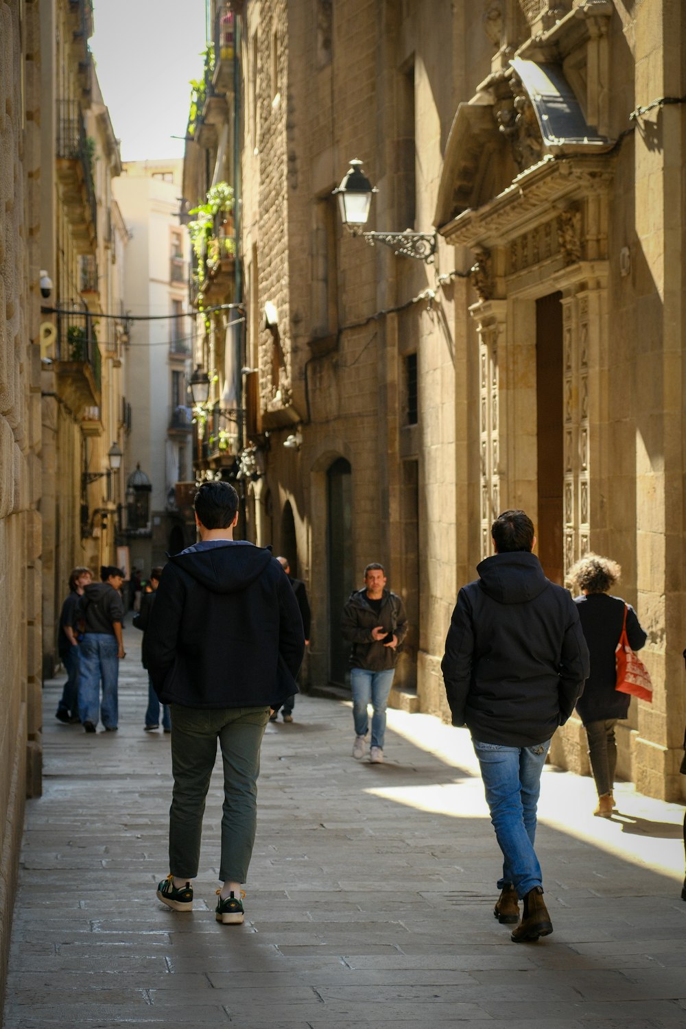 a group of people walking down a street next to tall buildings