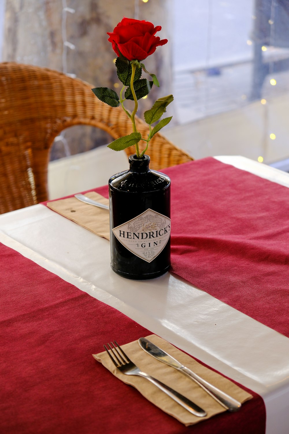 a single red rose in a black vase on a table