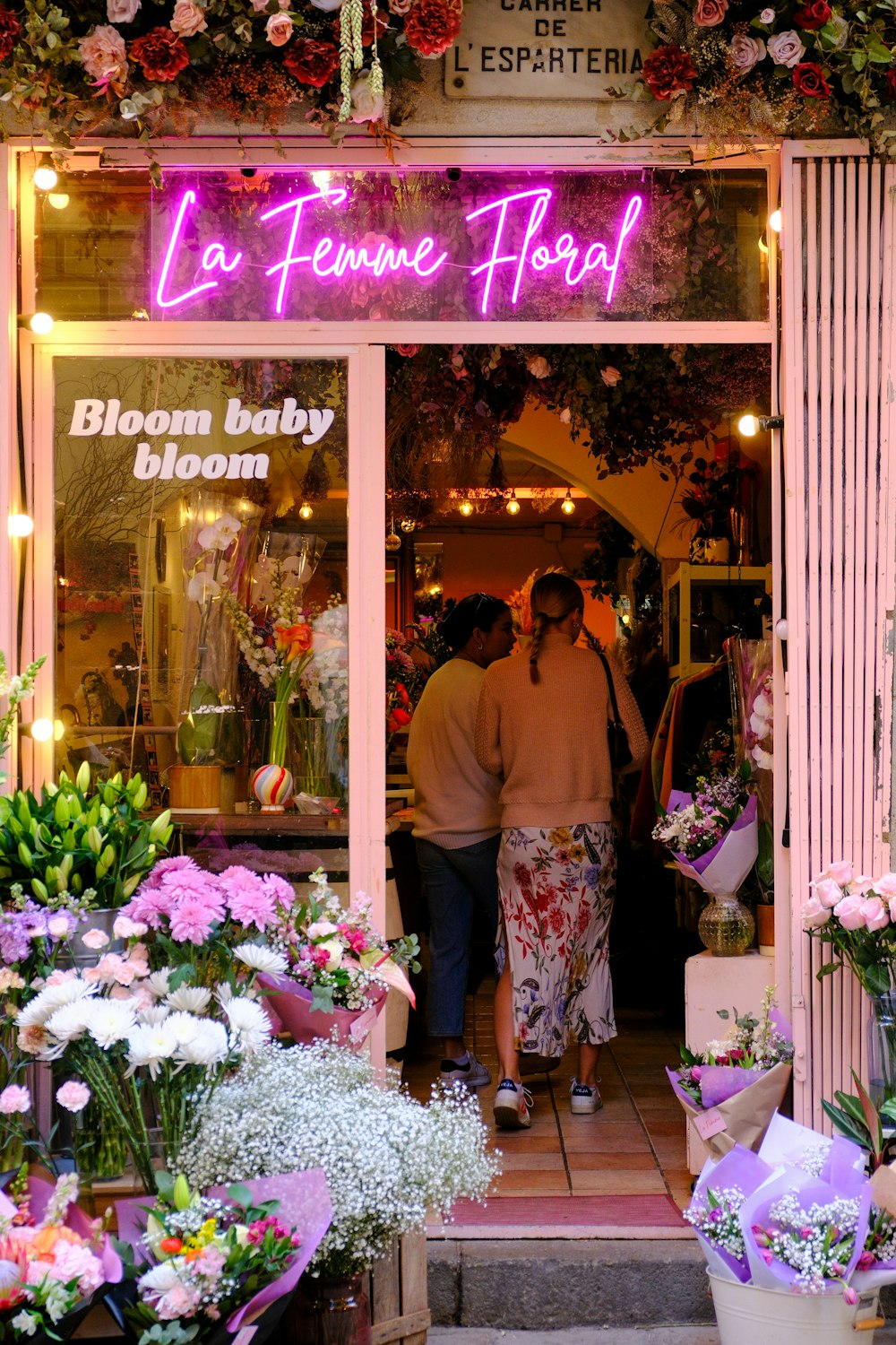 a couple of people that are standing outside of a flower shop